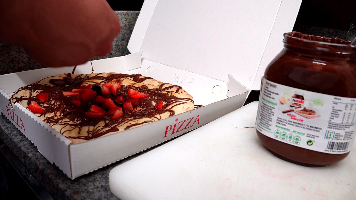 Süße Pizza mit Nutella, Erdbeeren und Banane im Karton